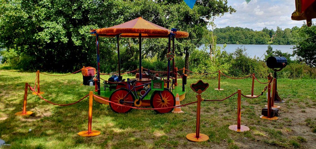 Petit manège artisanal entouré d’enfants sur une place de village